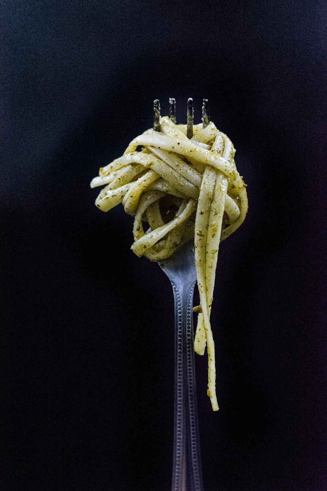 Gabel mit aufgedrehten Spaghetti vor dunklem Hintergrund
