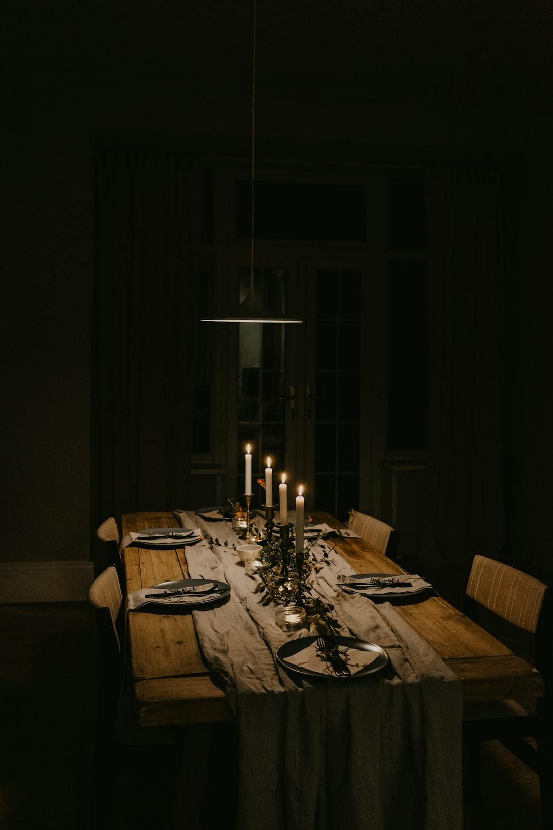 Dunkler Tisch mit Kerzen und Gläsern