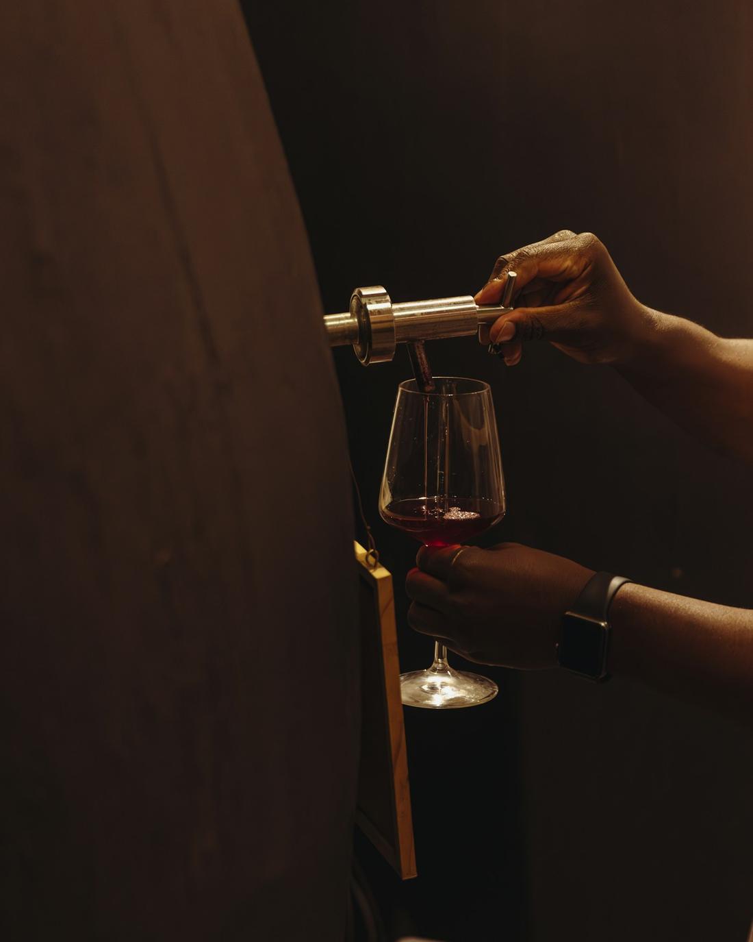Rotwein wird in ein Glas eingeschenkt