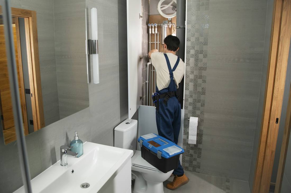 Monteur mit Werkzeugkoffer bei der Arbeit in einem Badezimmer